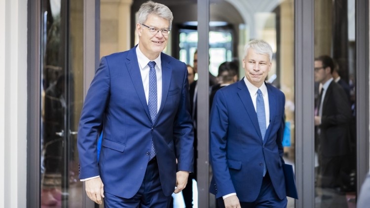 Patrick Schnieder and Steffen Bilger, both in blue suits, walk side by side out of a glass entrance at the ministry