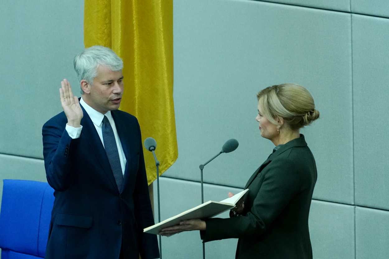 Steffen Bilger raises his right hand to take the oath of office in the Bundestag while Bundestag President Julia Klöckner holds the text in a folder in front of the federal flag