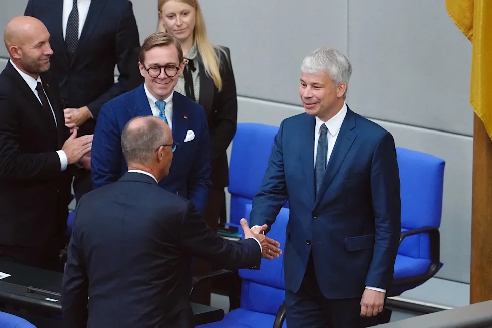 Steffen Bilger in the Bundestag plenary chamber, shaking hands with colleagues among the rows of blue seats
