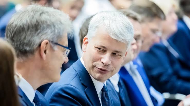 Steffen Bilger in conversation with a man in glasses, both standing among other members of parliament