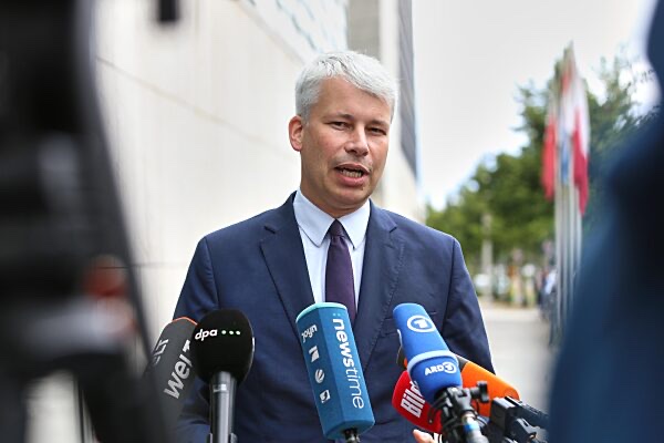 Steffen Bilger in a dark blue suit speaking outdoors into a cluster of broadcaster microphones, including dpa, Welt, ntv and ARD